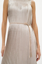 Woman wearing a silver beige pleated dress on a white background close up