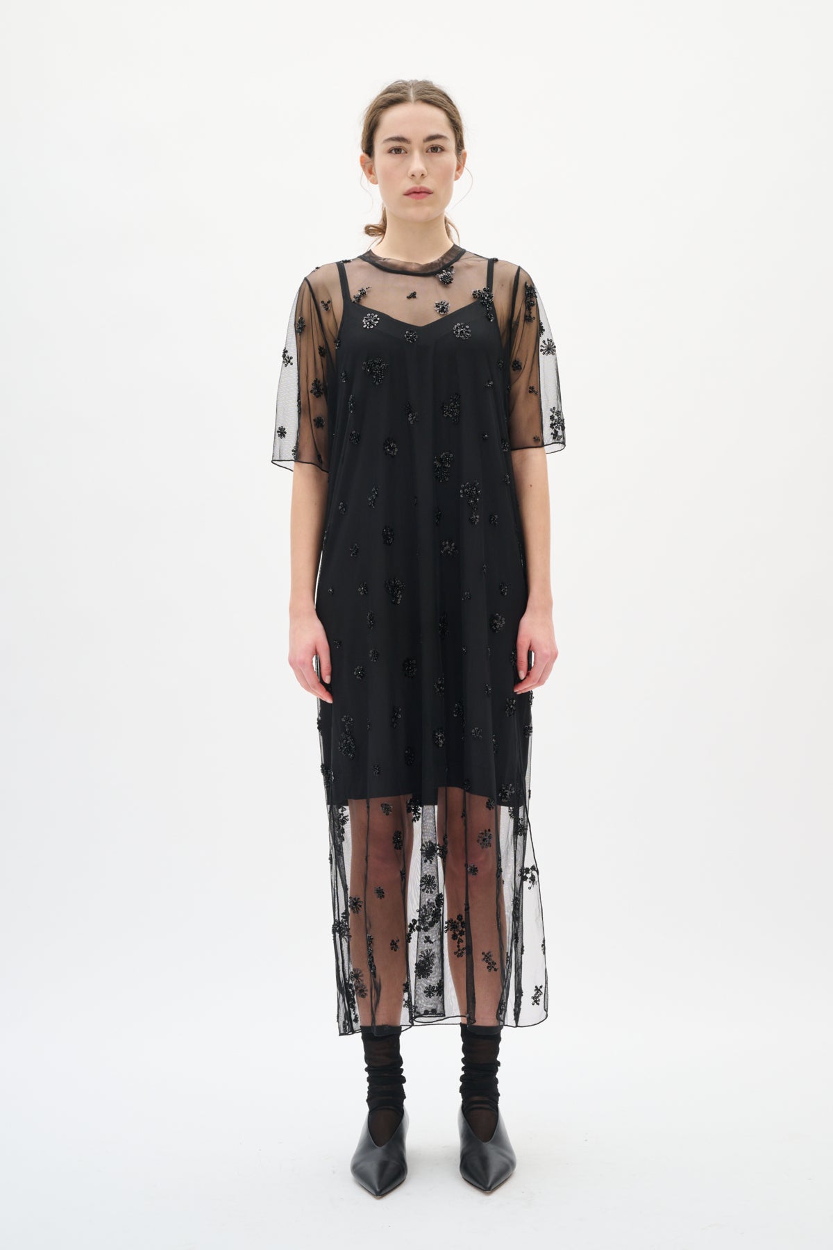 Black dress with sheer sleeves and bottom half on a white background