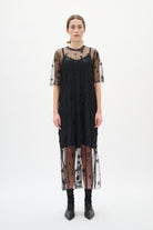 Black dress with sheer sleeves and bottom half on a white background