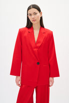 Woman wearing a red suit with a black button on a white background
