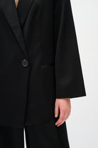 Black suit jacket worn by a person on a white background