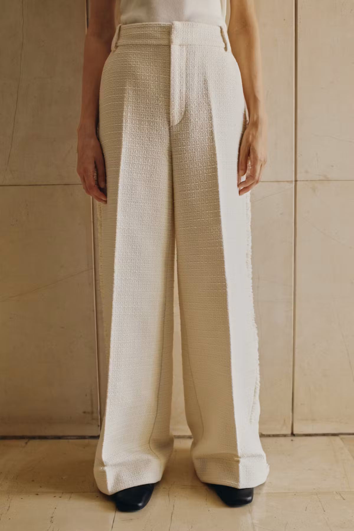Person wearing beige and white pants against a neutral background