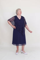 Woman wearing a dark blue dress with beaded details on a white background