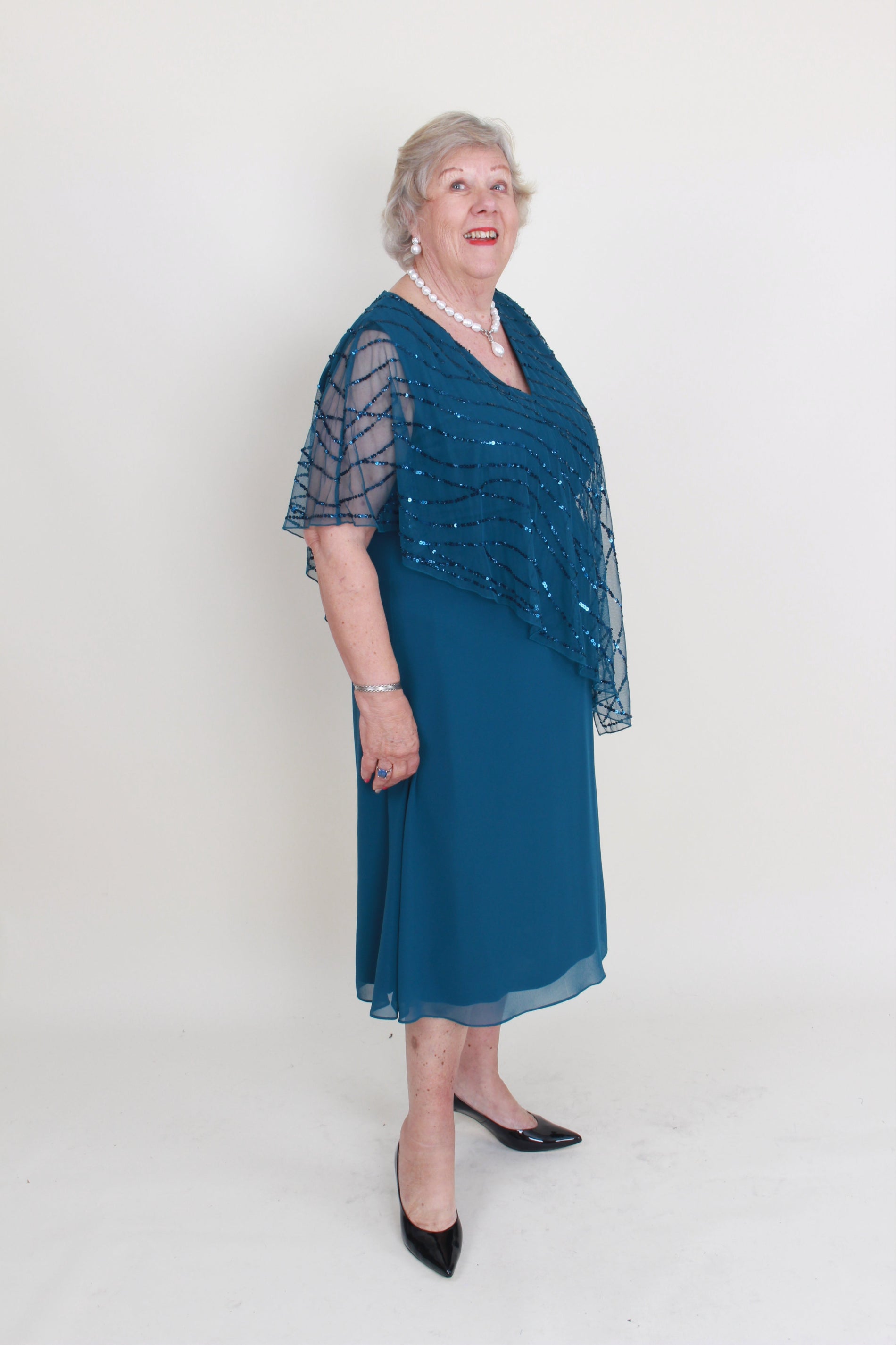 Woman wearing an emerald dress with a matching shawl on a white background