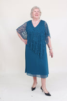 Woman wearing a green dress with a beaded overlay on a white background