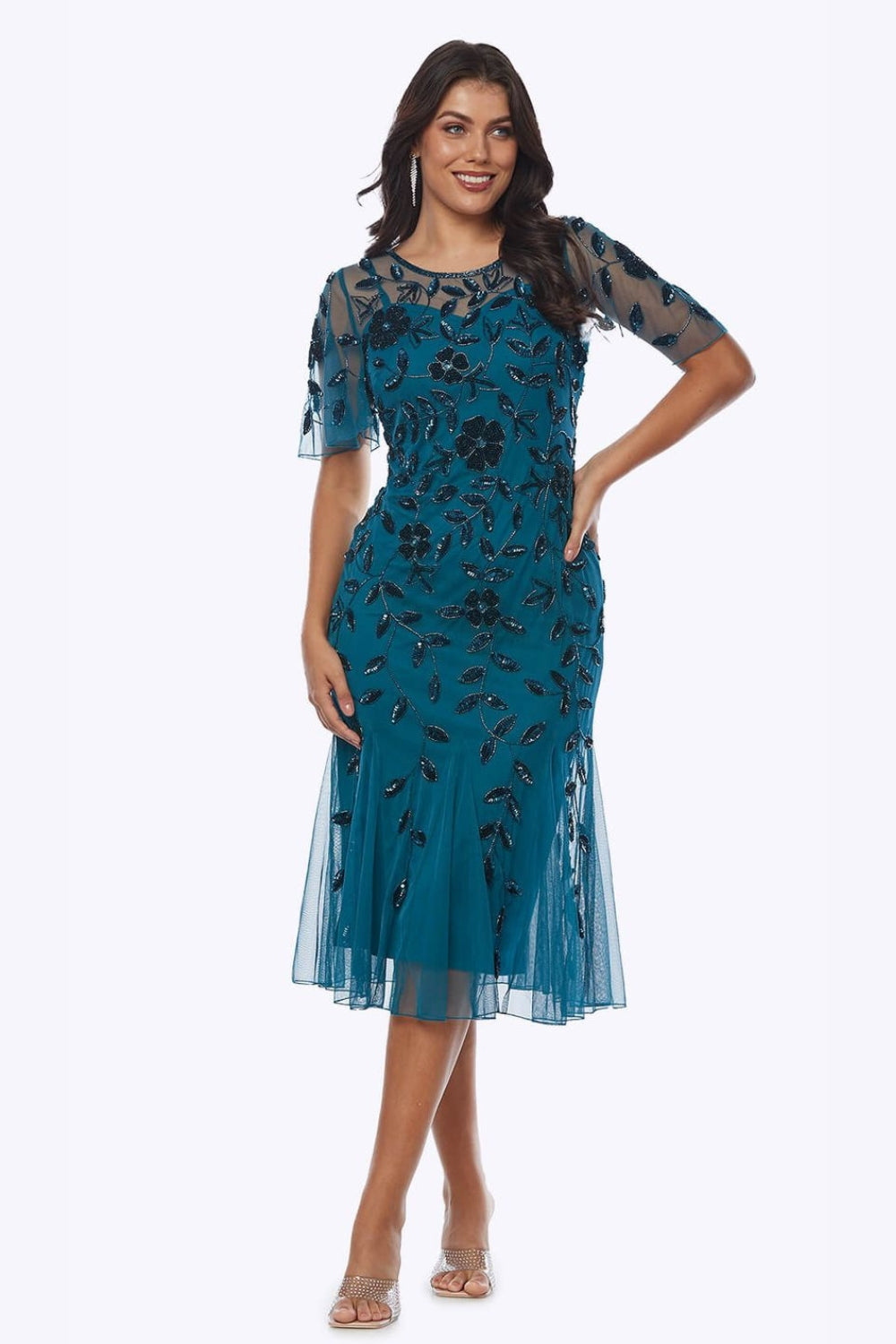 Woman wearing a teal beaded floral dress on a white background