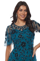 Woman wearing a teal beaded floral dress on a white background close up