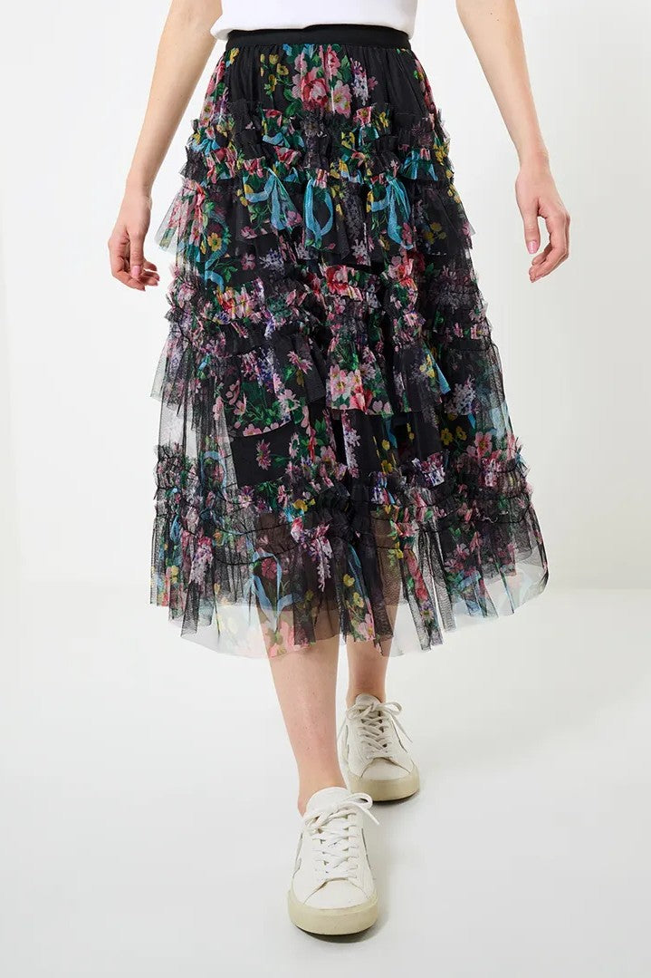 Person wearing a floral tiered skirt with white sneakers on a white background