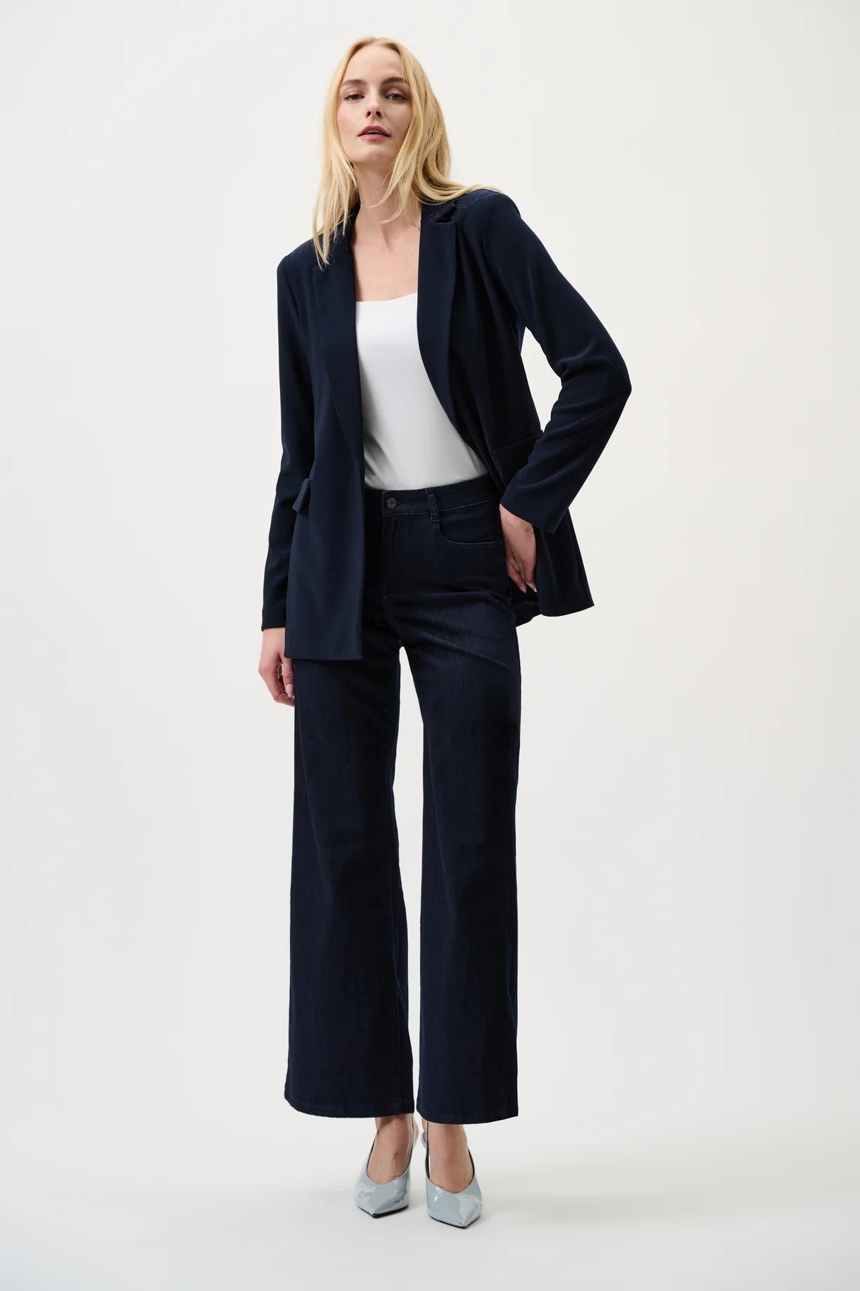 Woman wearing dark blue jacket and jeans with a white top on a white background