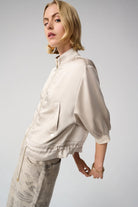 Woman wearing a beige satin jacket and pants on a white background side angle