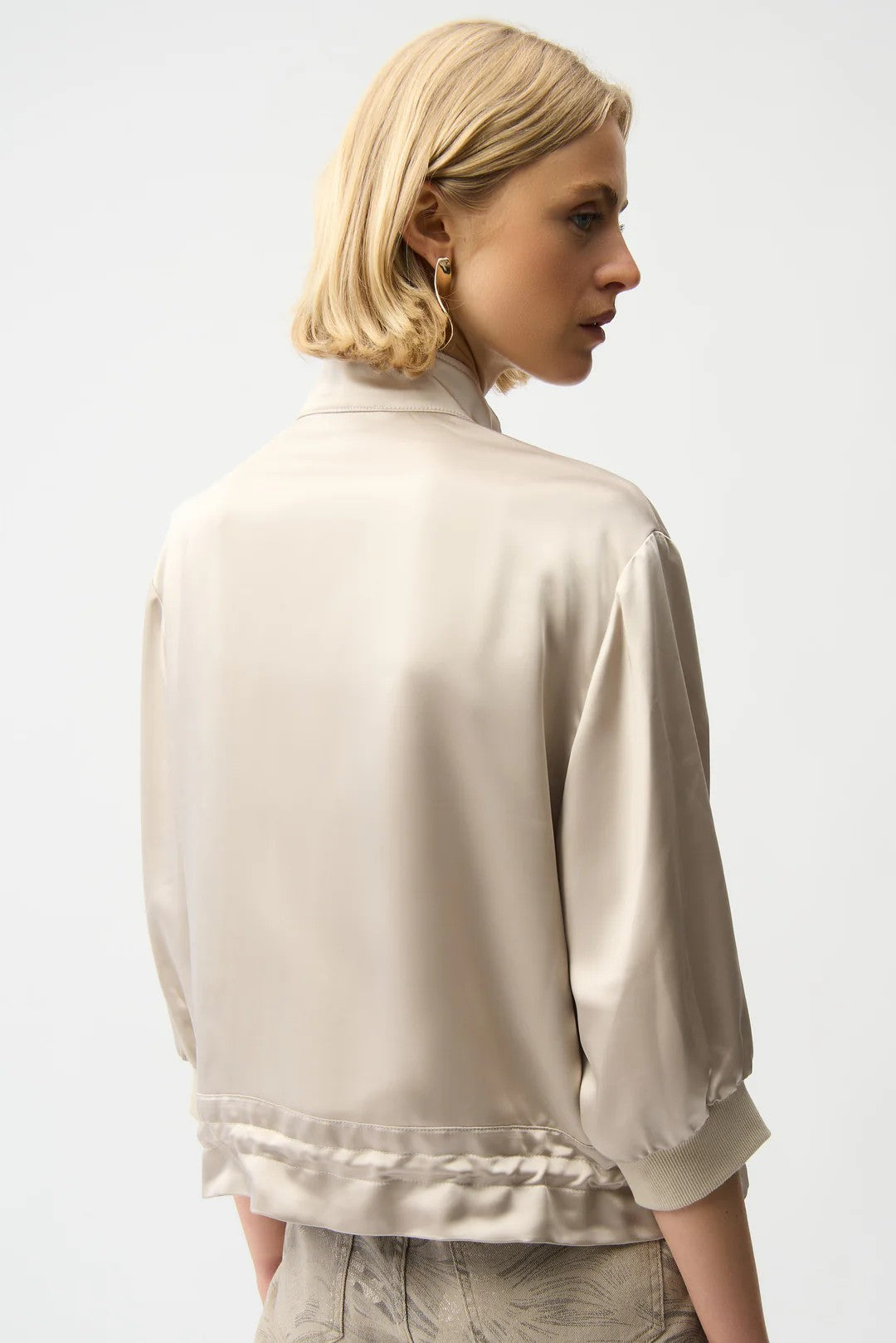 Woman wearing a beige satin jacket and pants on a white background back angle
