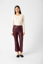 Woman wearing a white top and maroon pants on a white background