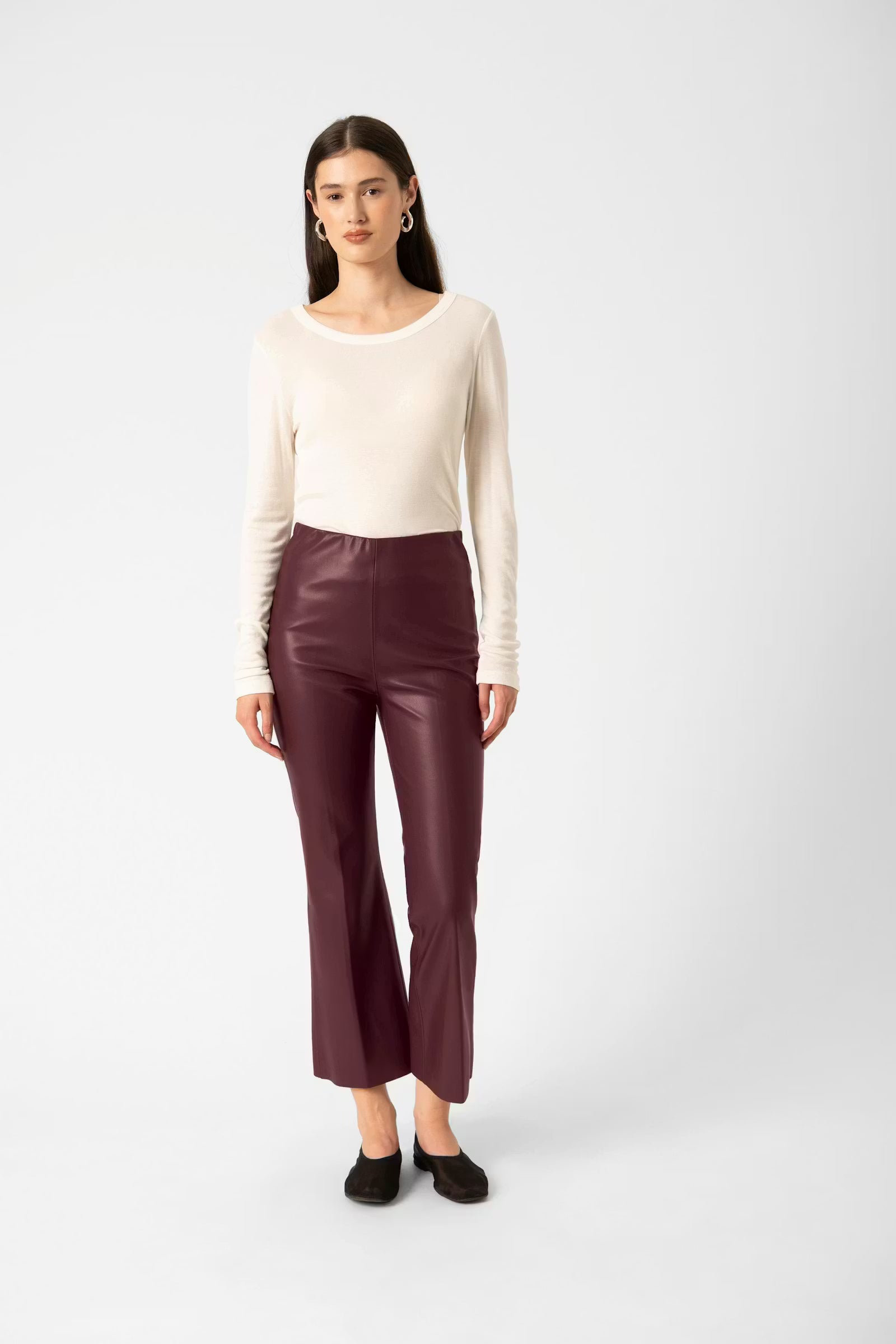 Woman wearing a white top and maroon pants on a white background