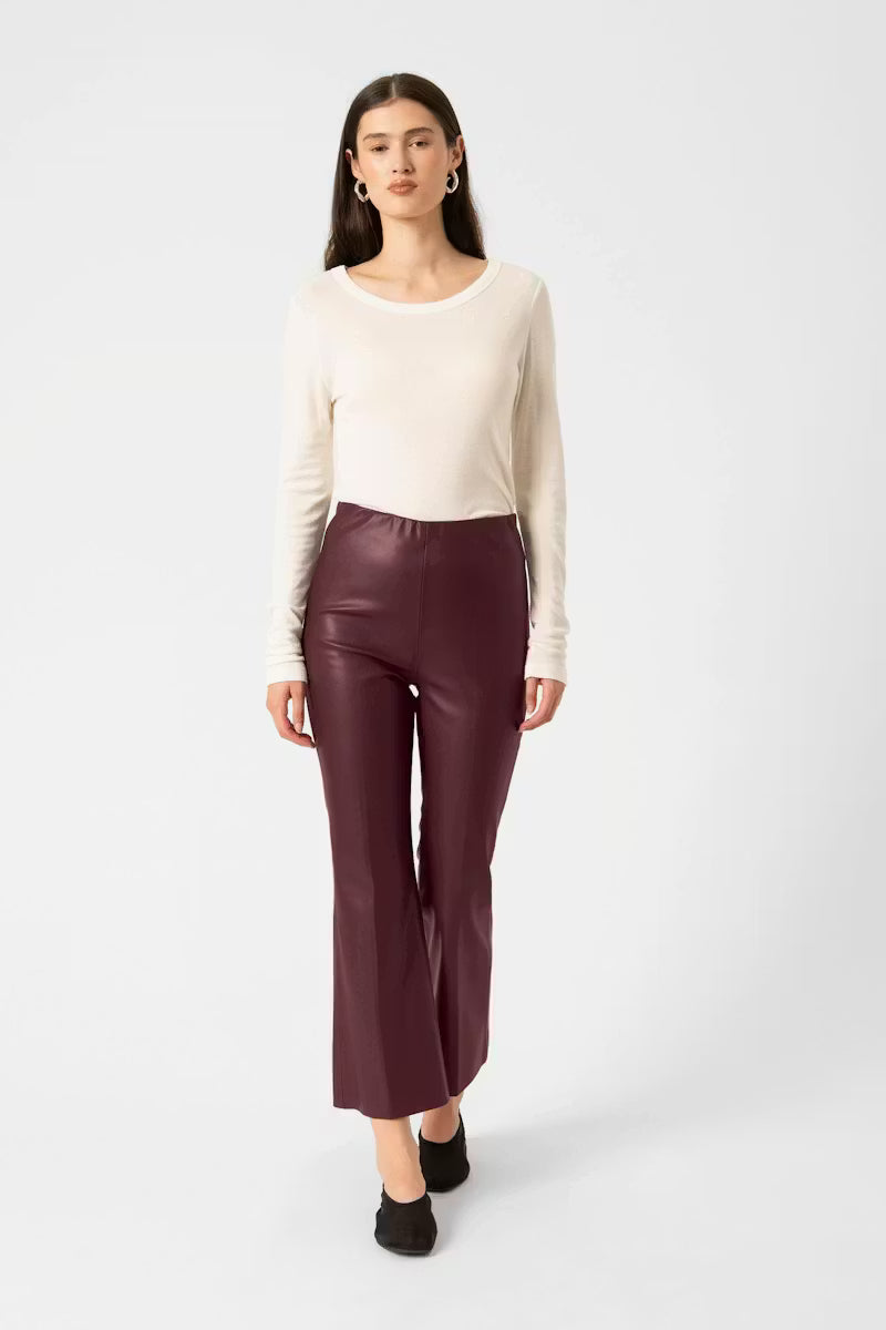 Woman wearing a cream sweater and burgundy pants on a white background