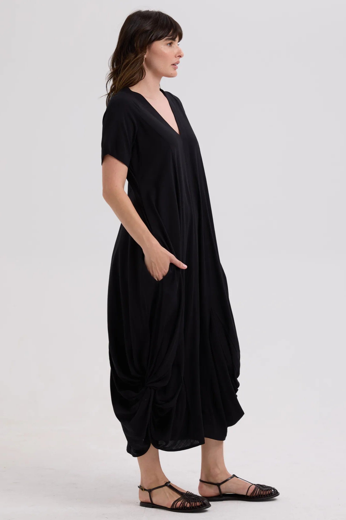 Woman wearing a black dress with a draped effect on a white background
