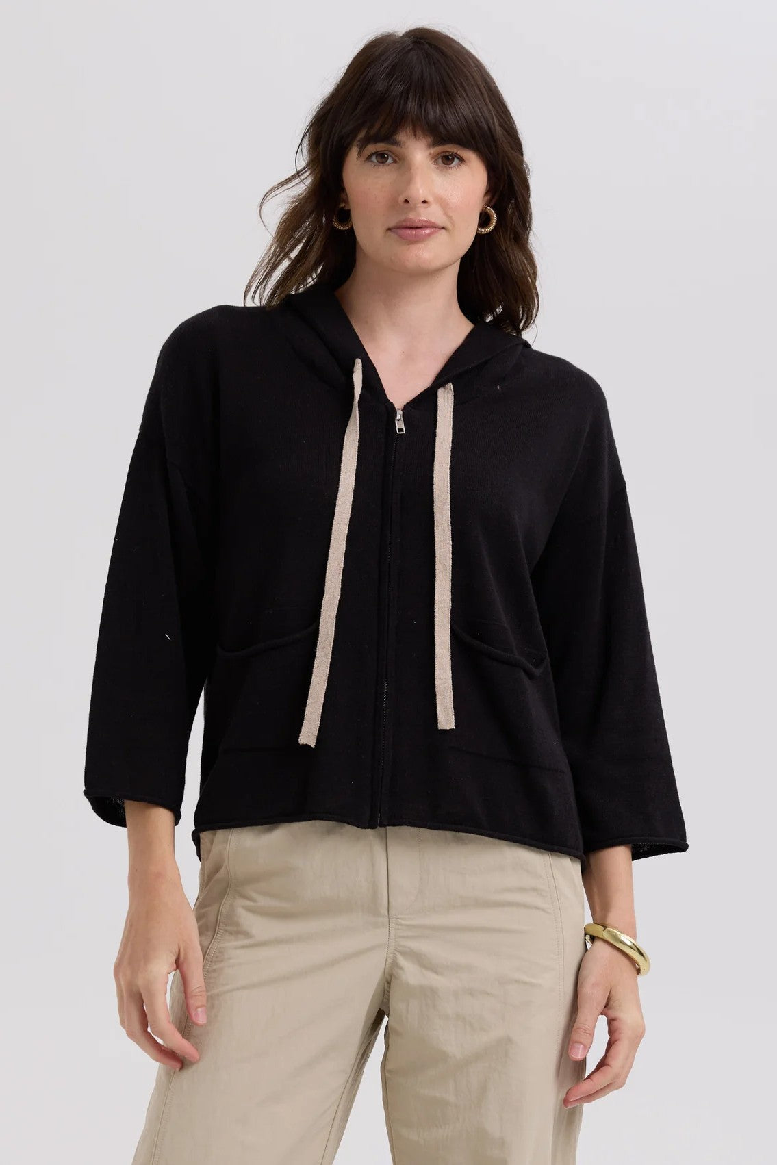 Woman wearing a black hoodie with beige drawstrings on a white background