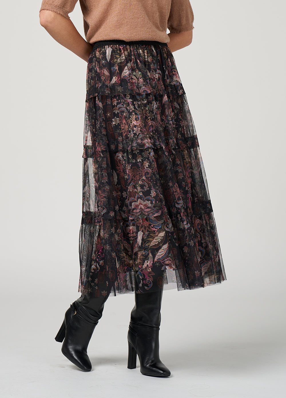 Person wearing a floral skirt and black boots on a plain background