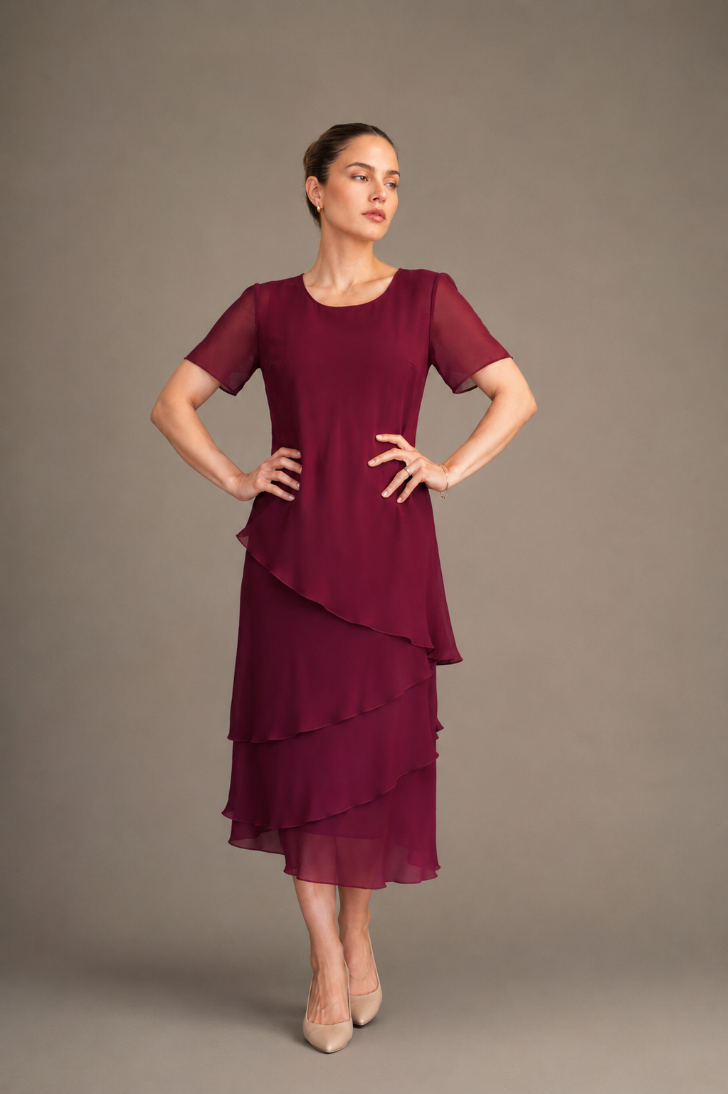 Woman wearing a burgundy dress with layered skirt against a plain background