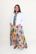 Woman wearing a white jacket and colorful floral dress on a white background