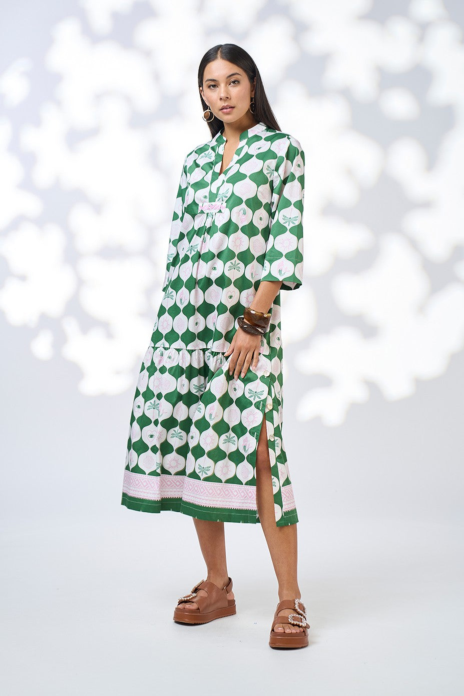 Woman wearing a green and white patterned dress against a light background