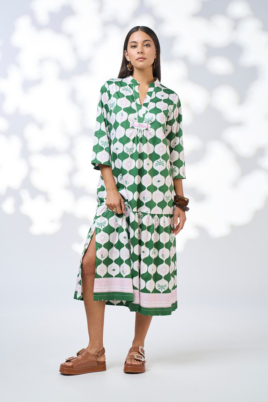 Woman wearing a green and white patterned dress against a white background