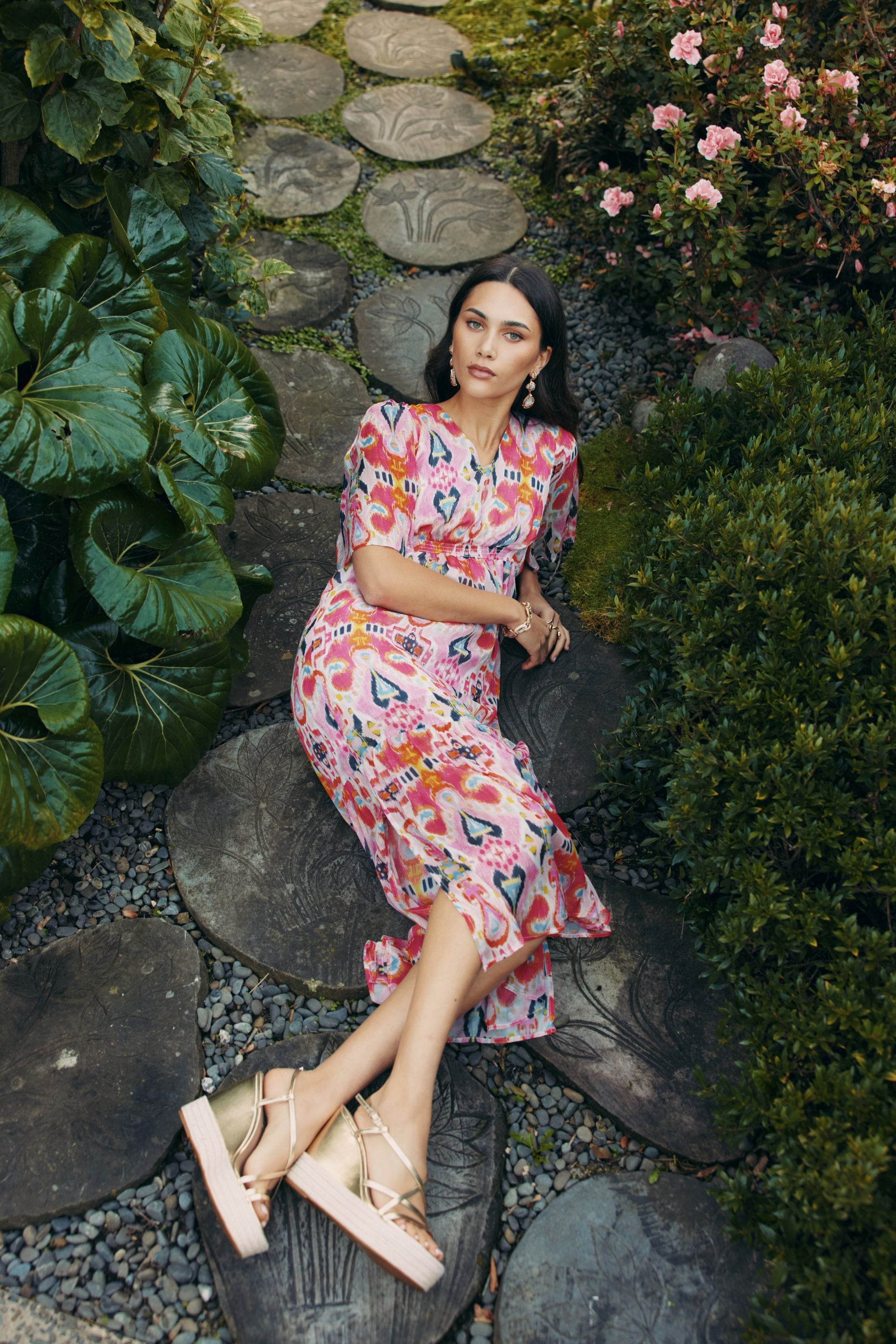 Woman in a colorful dress sitting on stone steps in a garden