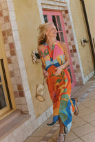 model wearing multi colour maxi dress in front of pink door