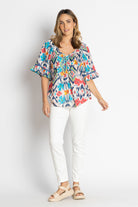 multi print gathered blouse and white jeans worn by model 