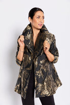Woman wearing a black and gold patterned jacket on a white background