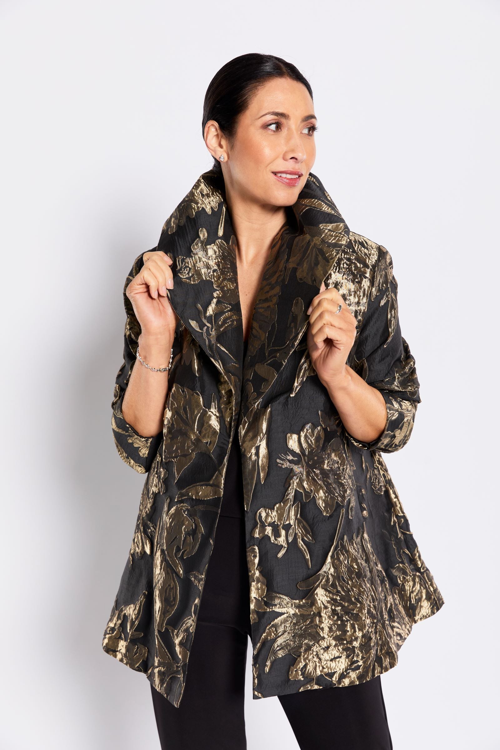 Woman wearing a black and gold patterned jacket on a white background