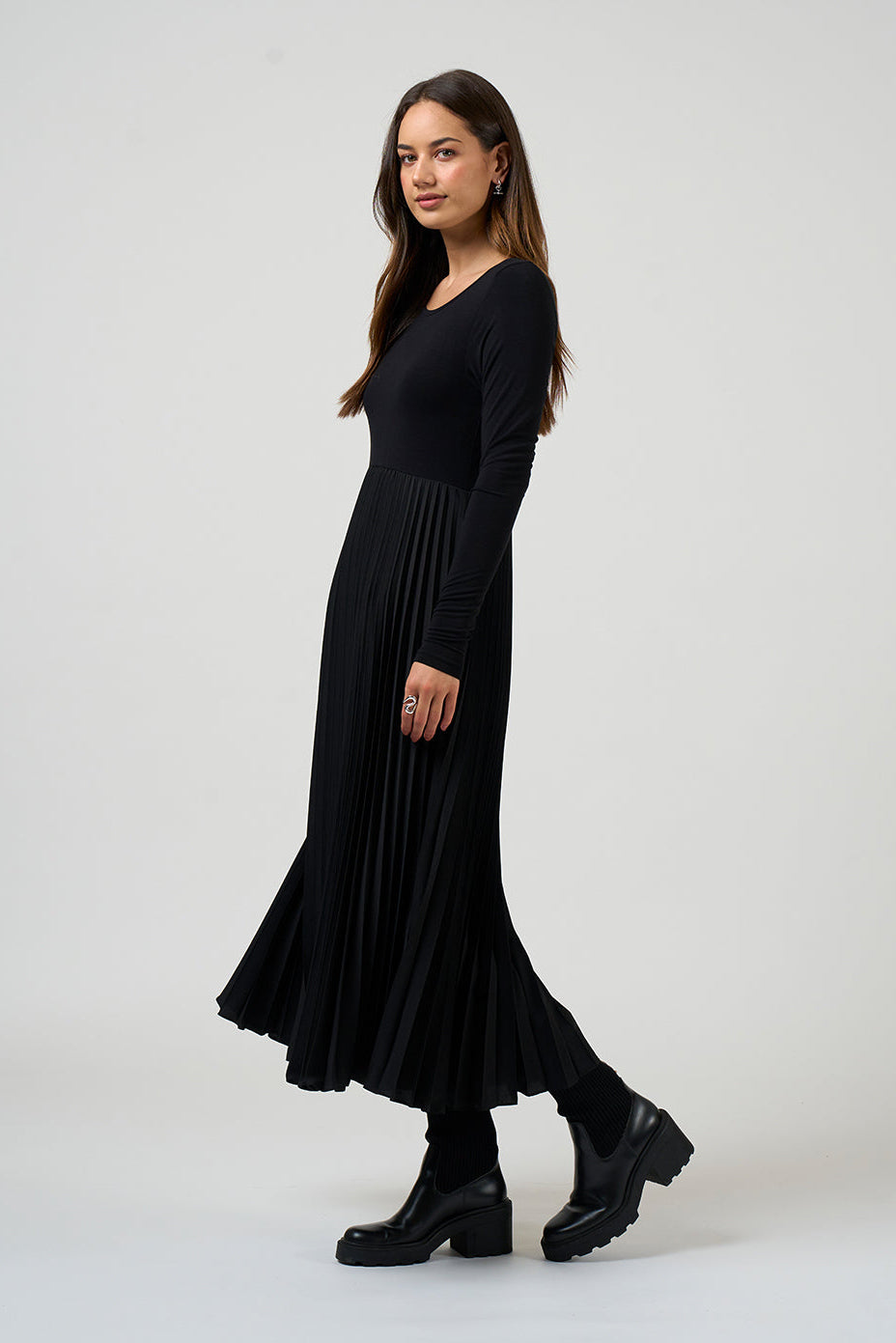 Woman wearing a black dress standing against a white background