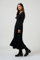 Woman wearing a black dress standing against a white background
