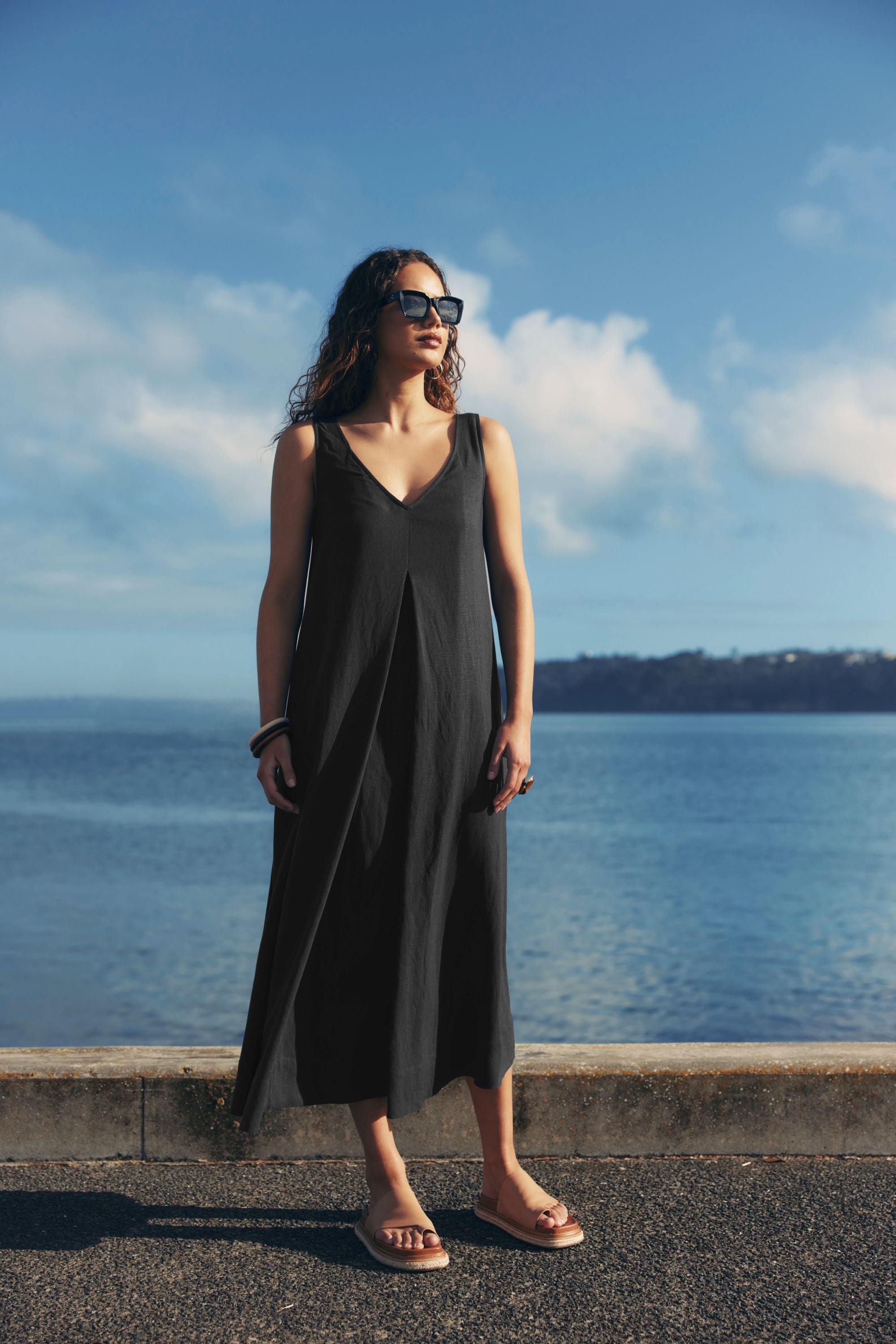 pleat maxi dress black worn by model ocean background
