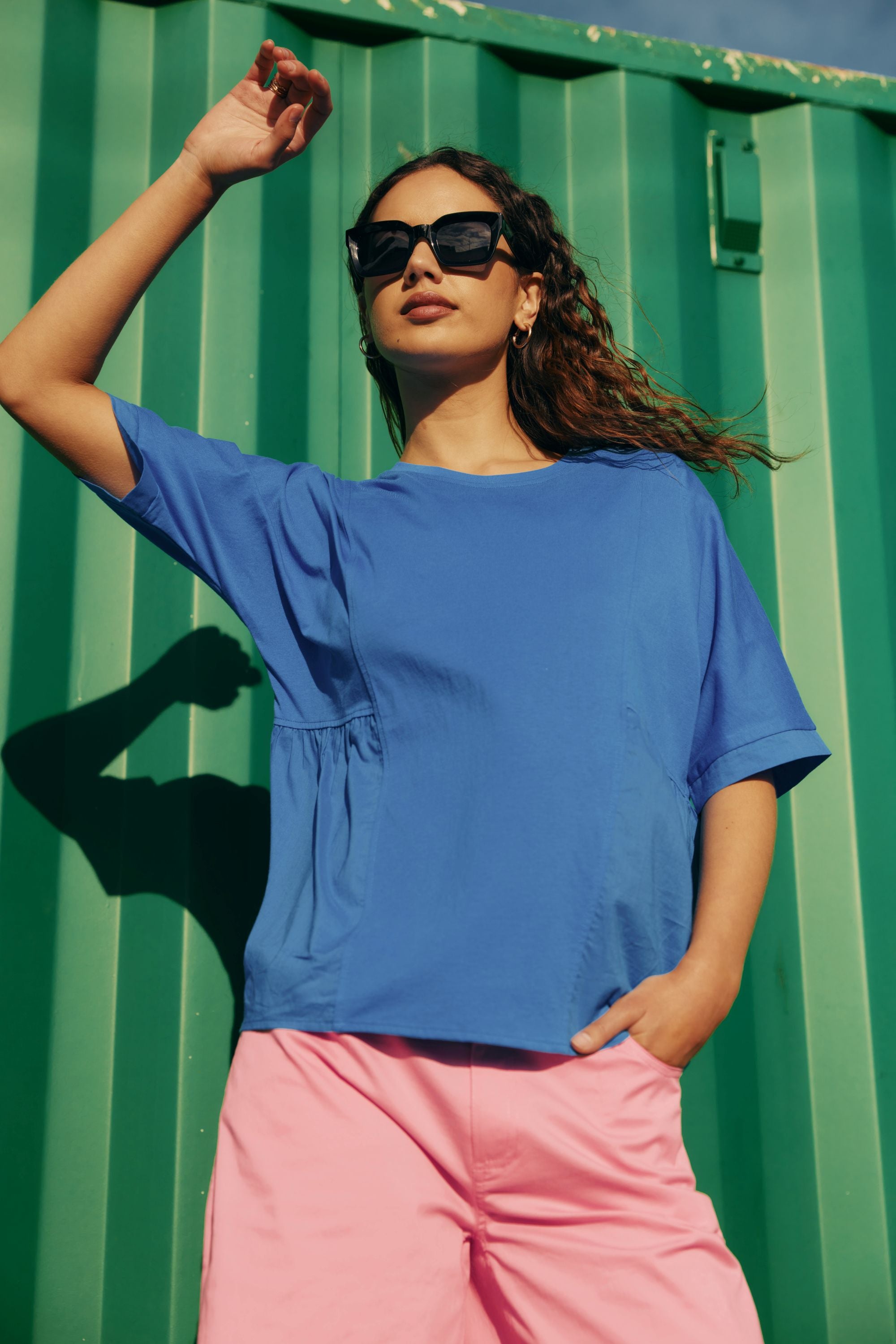 blue shirt with pink pant worn by model against green outddor background
