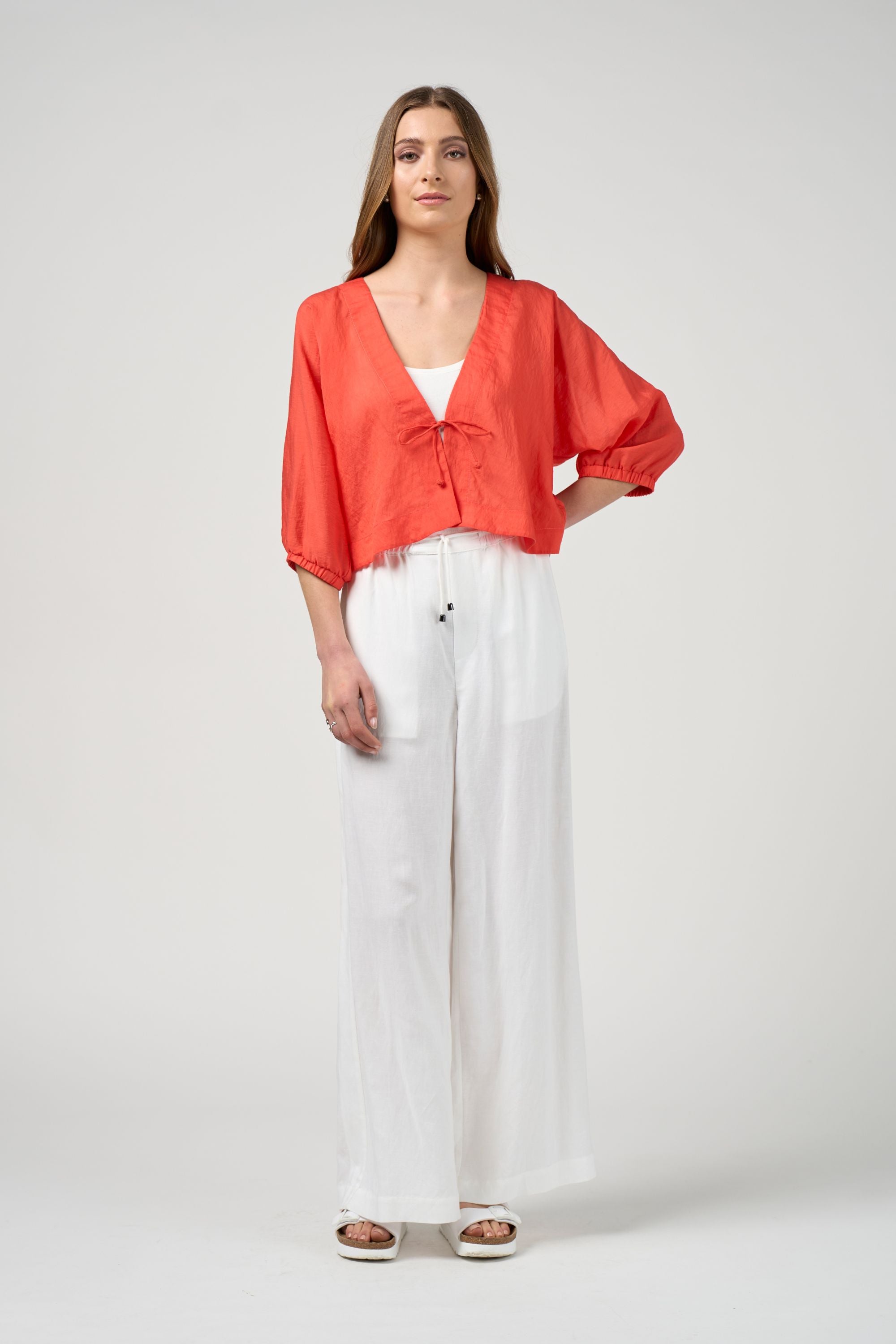 orange tie jacket with white pant worn by model 