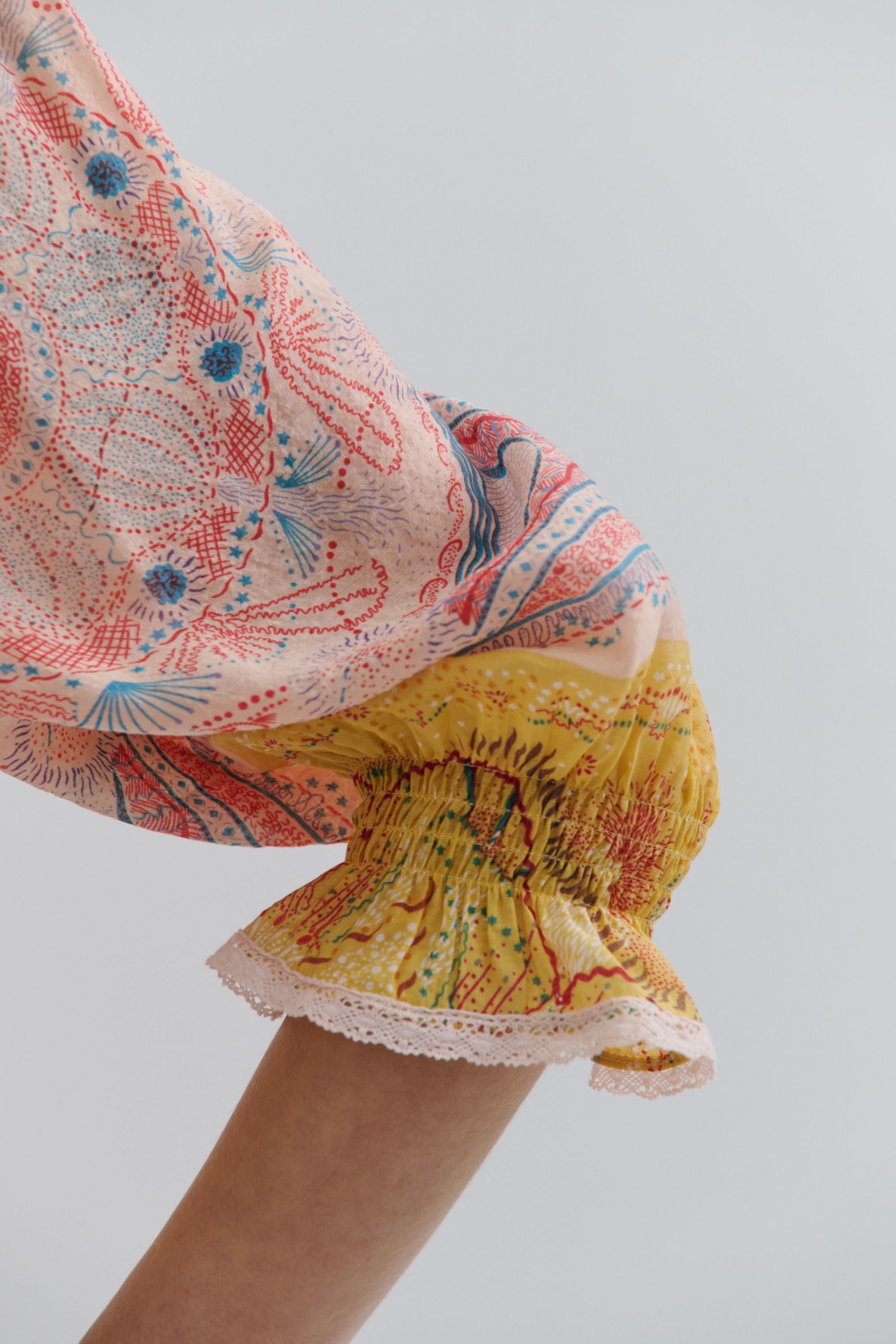 Colorful patterned fabric with a focus on a yellow and red design against a plain background