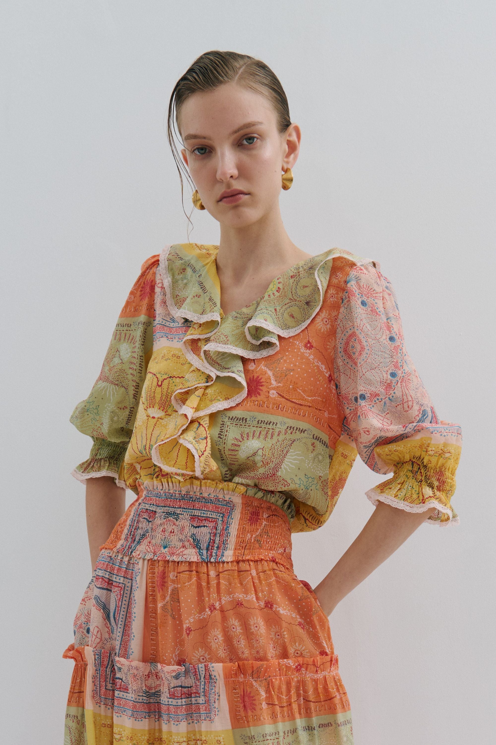 Woman wearing a colorful patterned dress against a plain background