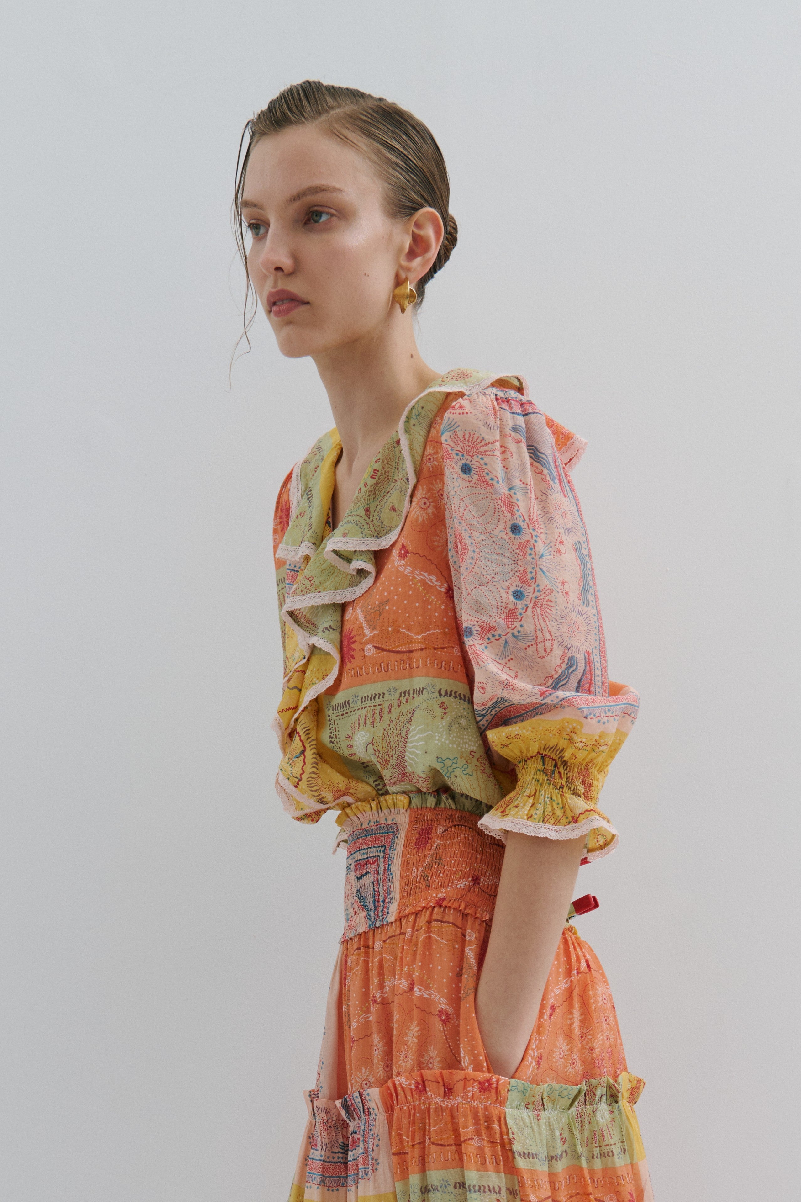 Woman wearing a colorful patterned top against a plain background
