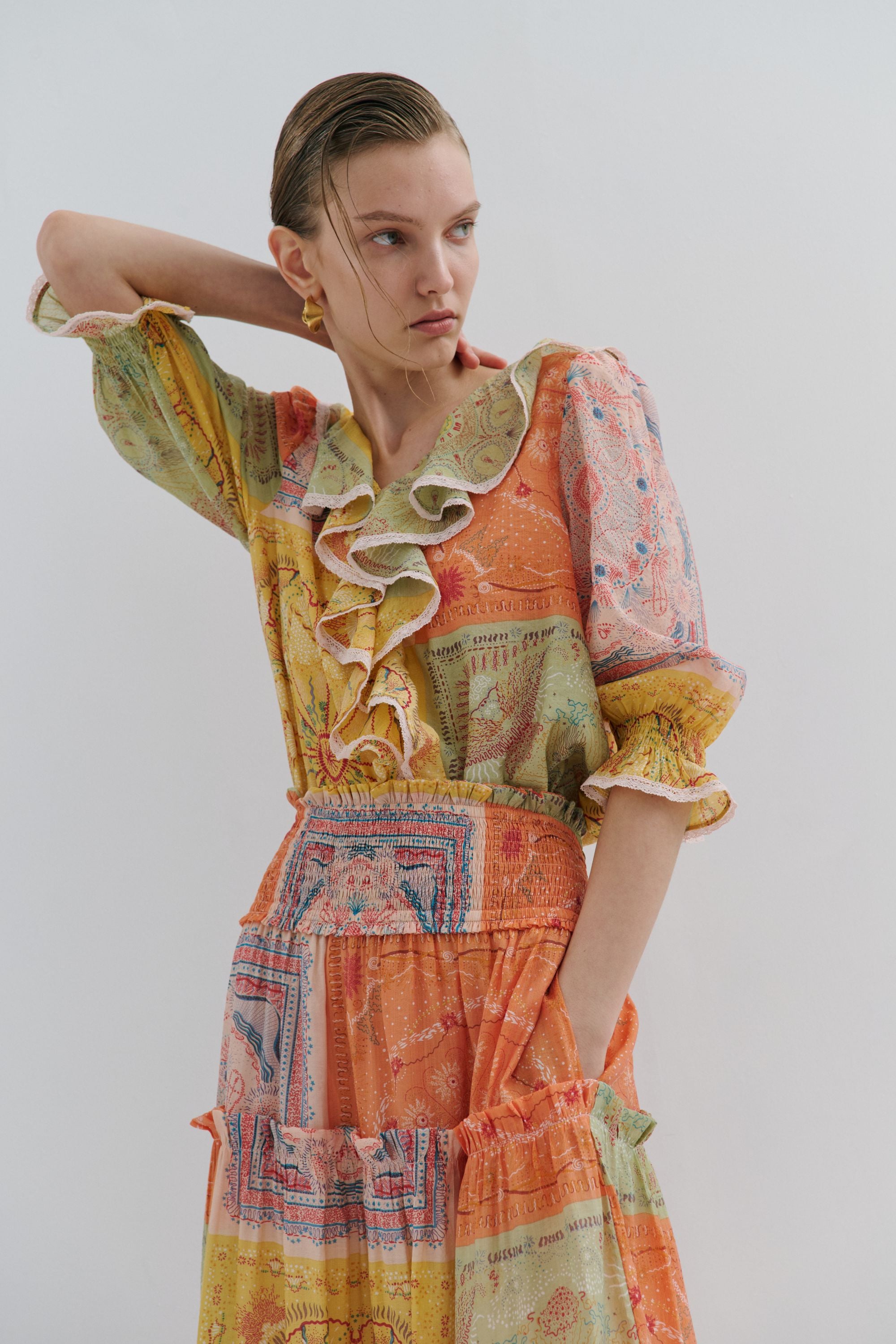 Woman wearing a colorful patchwork dress against a plain background