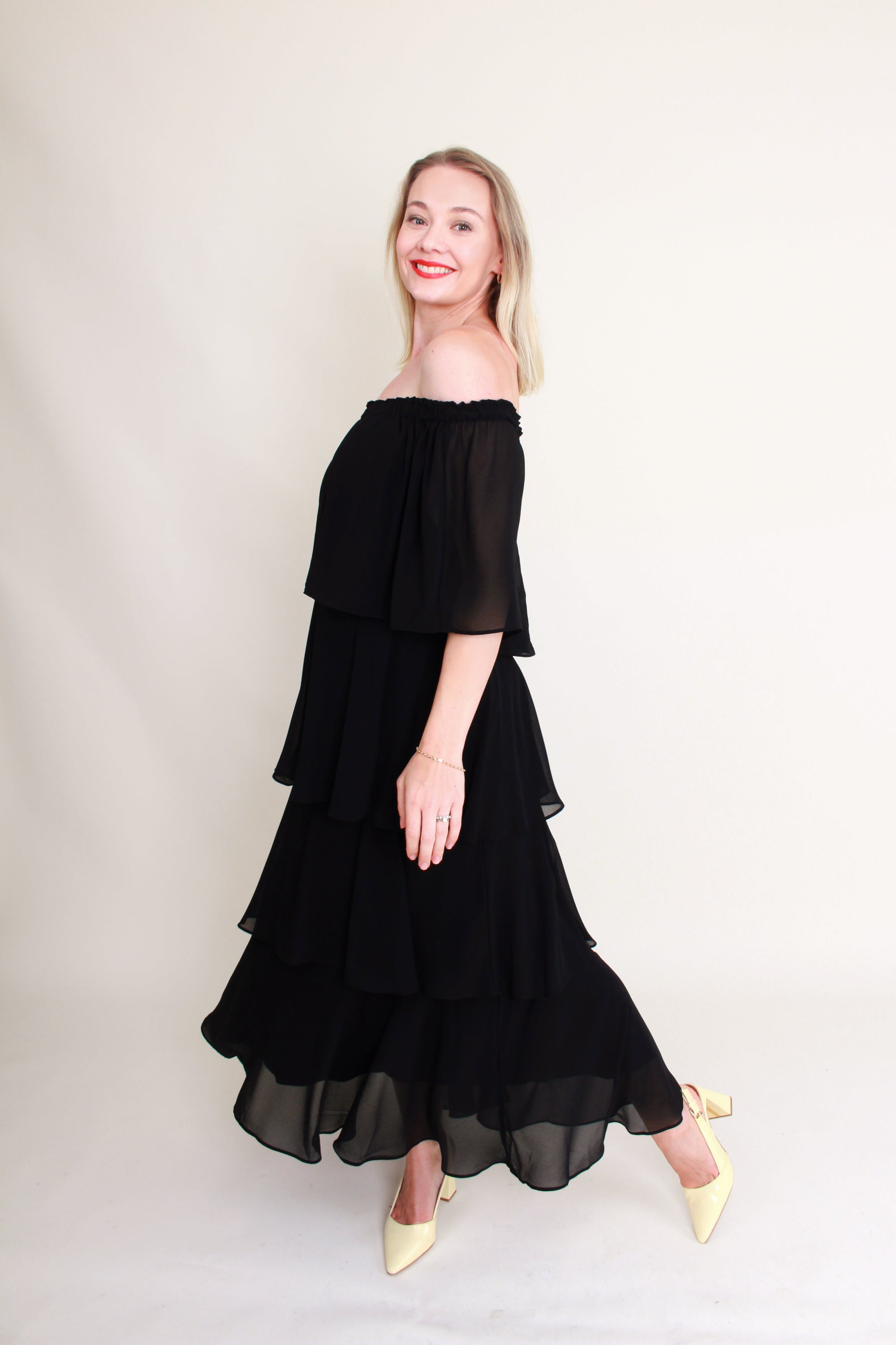 Woman wearing a black off-shoulder dress against a plain background