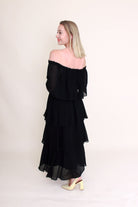 woman wearing off the shoulder black dress back view plain background