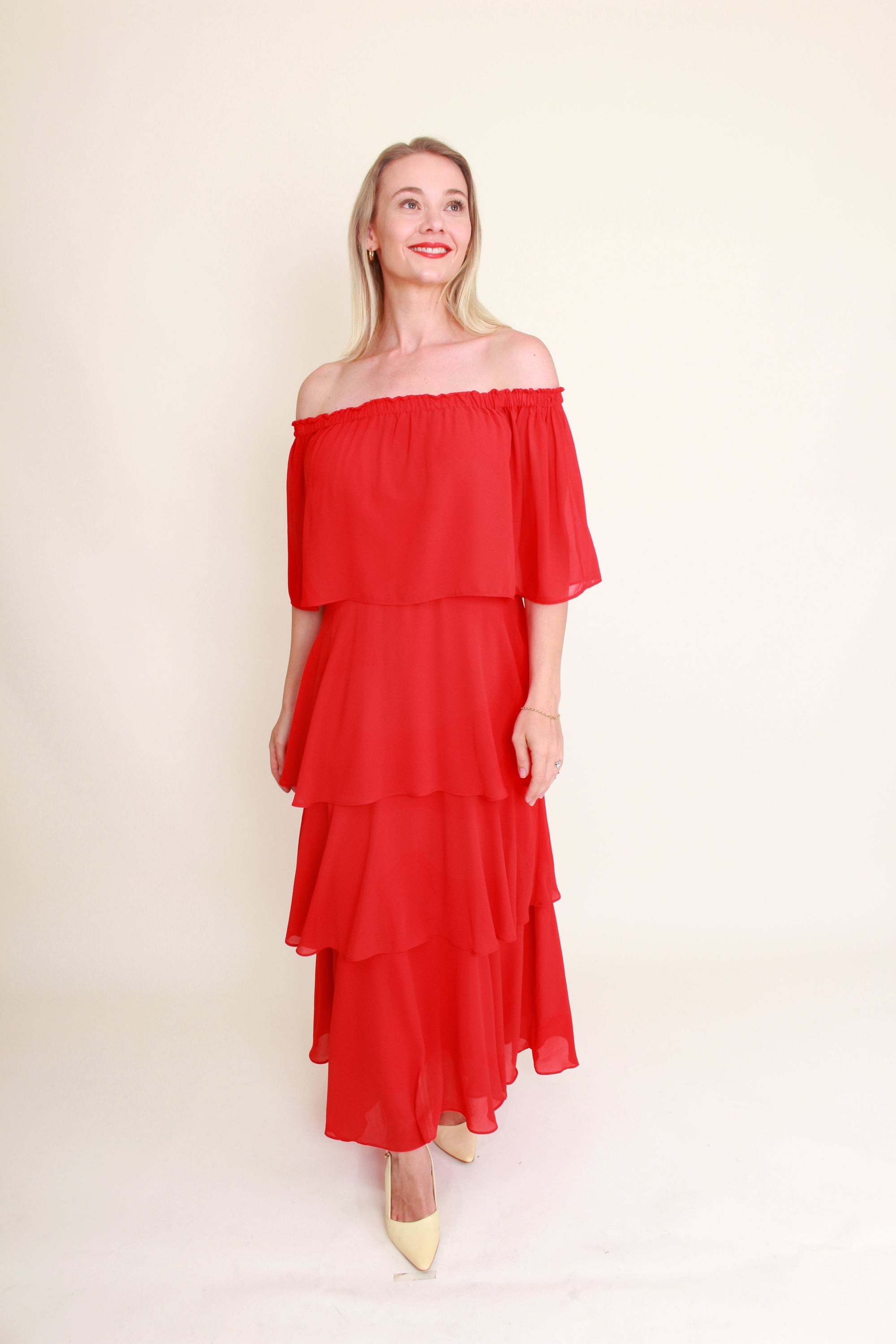 Woman wearing a red off-shoulder dress against a plain background
