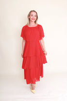 woman wearing red tiered dress against plain background
