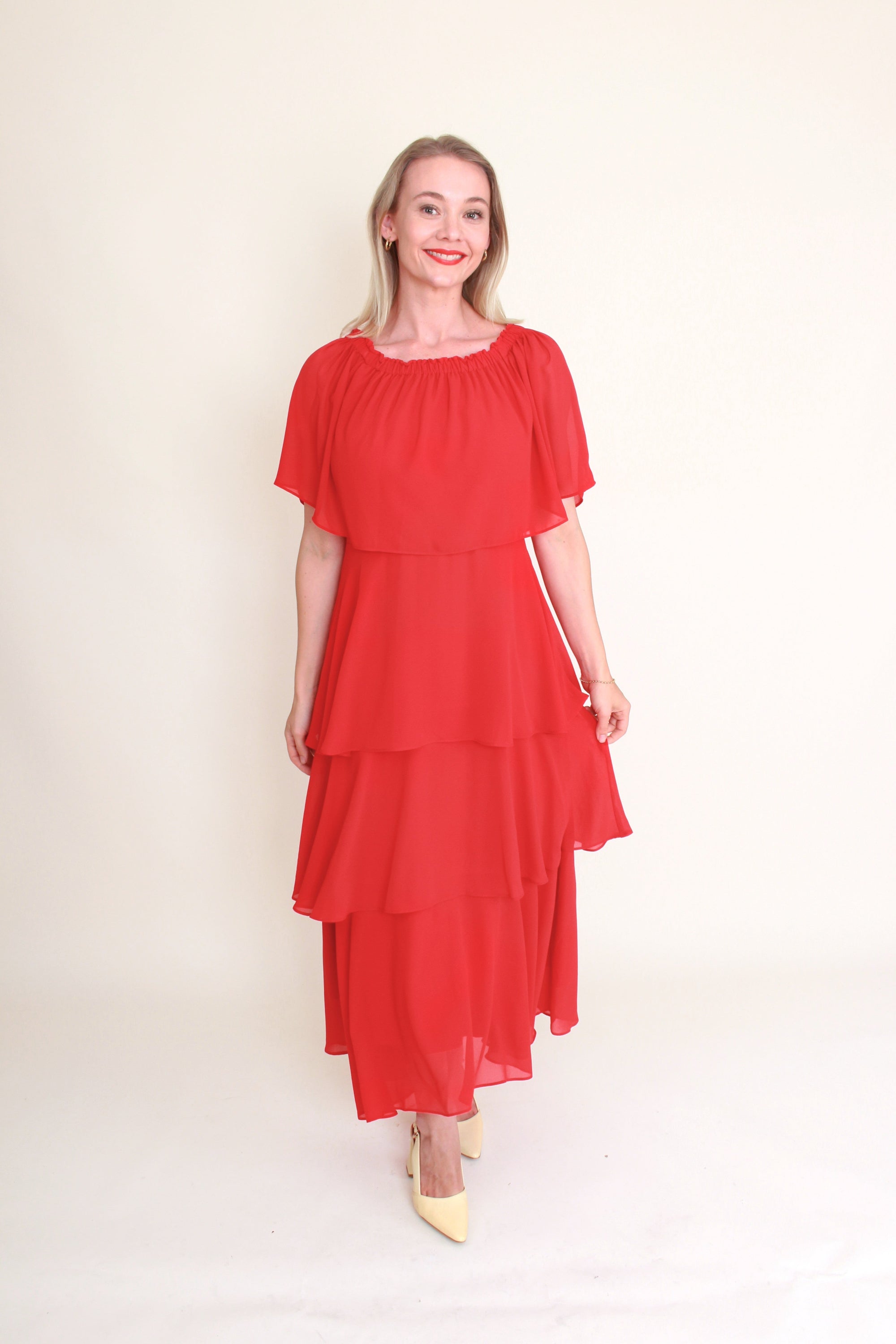 woman wearing red tiered dress against plain background