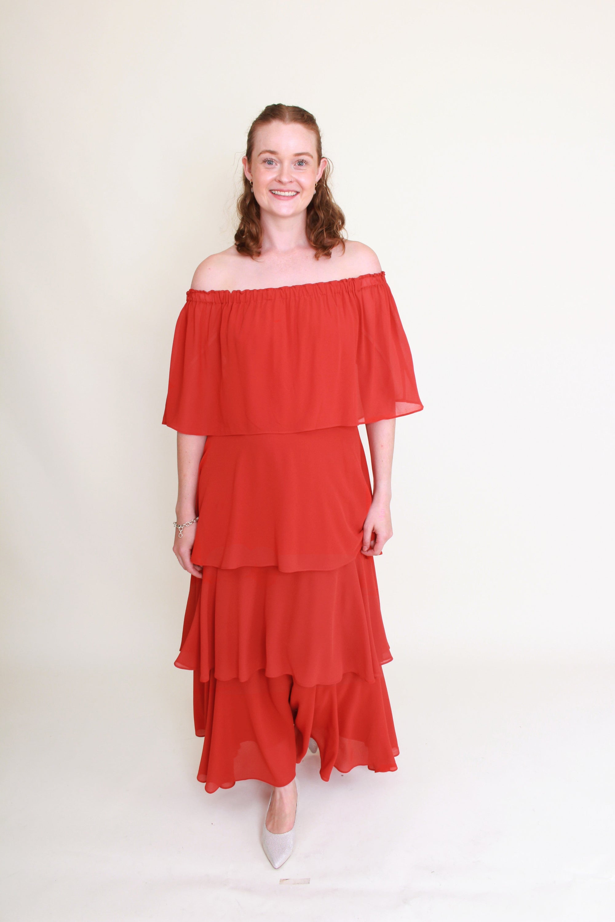 Woman wearing a red off-shoulder dress against a white background