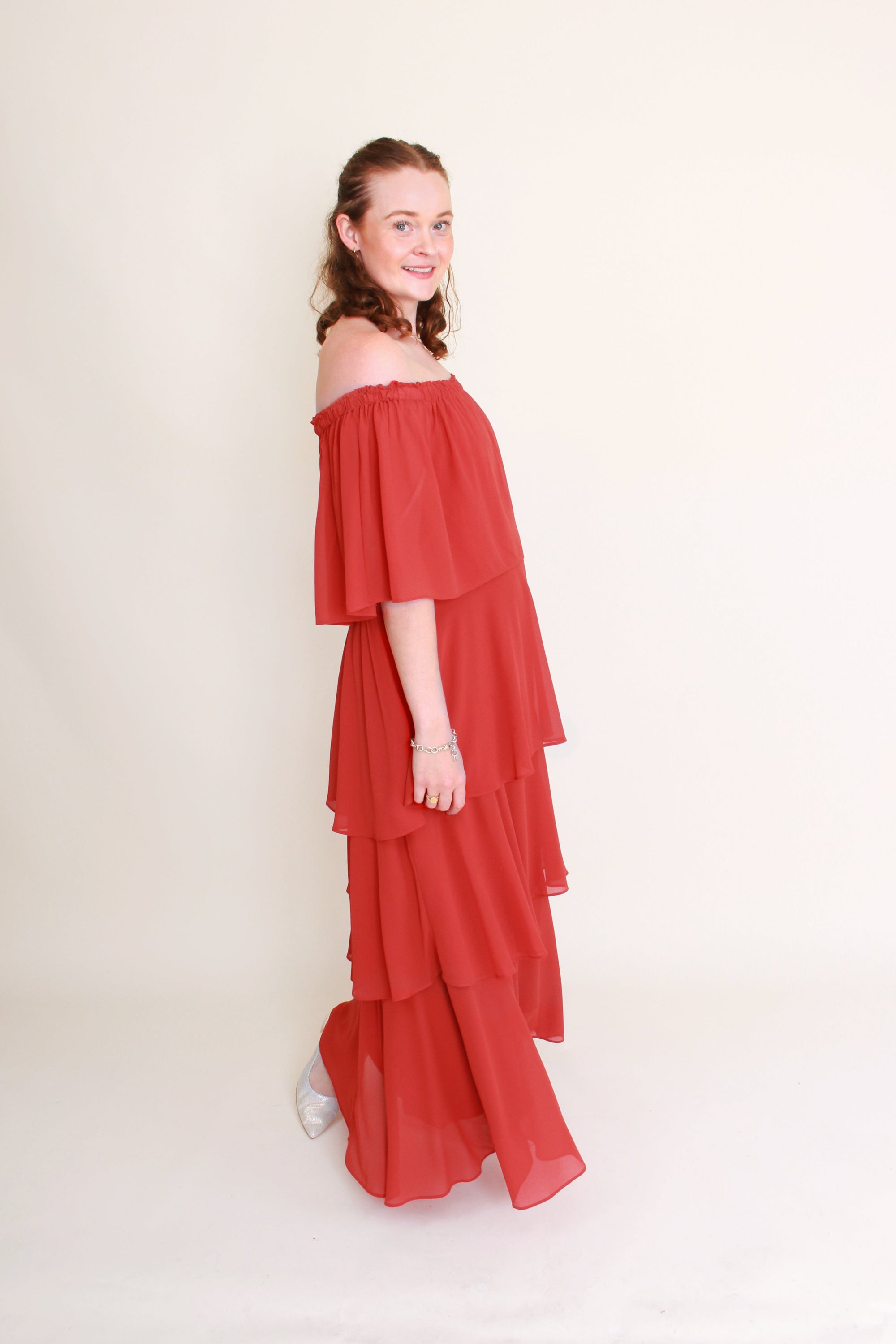 Woman wearing a red off-shoulder dress against a plain background