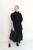 black maxi skirt rosette detail with black knit top worn by model 