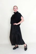 black maxi skirt rosette detail with black knit top worn by model 