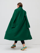 Person wearing a long green coat on a white background