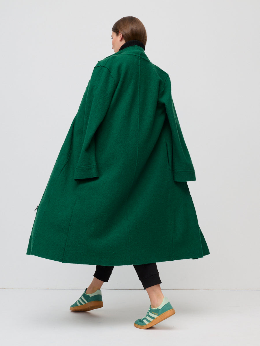 Person wearing a long green coat on a white background